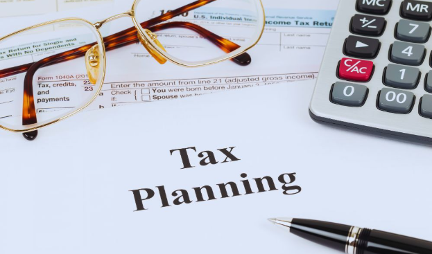 A desk setup with a document titled "Tax Planning," IRS forms, calculator, and pen, representing customized tax plans for business owners.