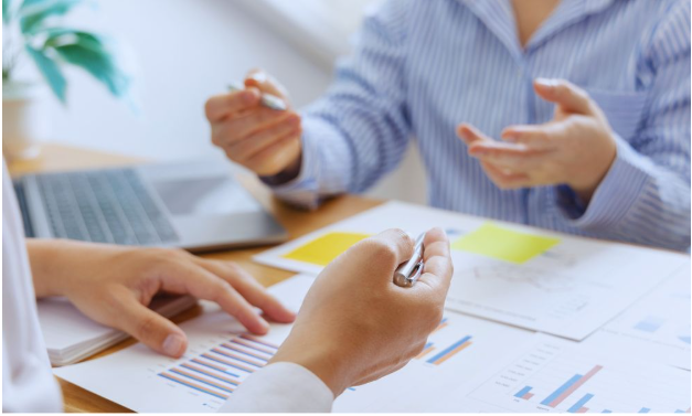 Small business growth consultant and client in a collaborative planning session, seated at a table with documents and notes for improving daily operations.